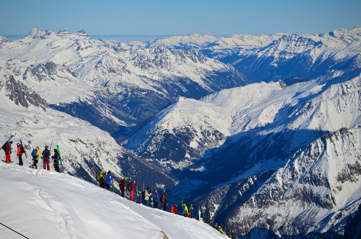 Group of skiers on a ridge above a glacier valley