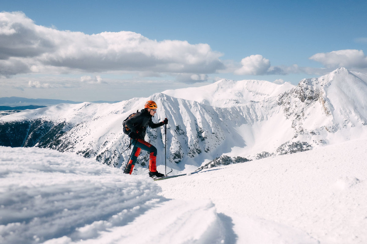 Ski tourer with a backpack crossing a snowy ridge