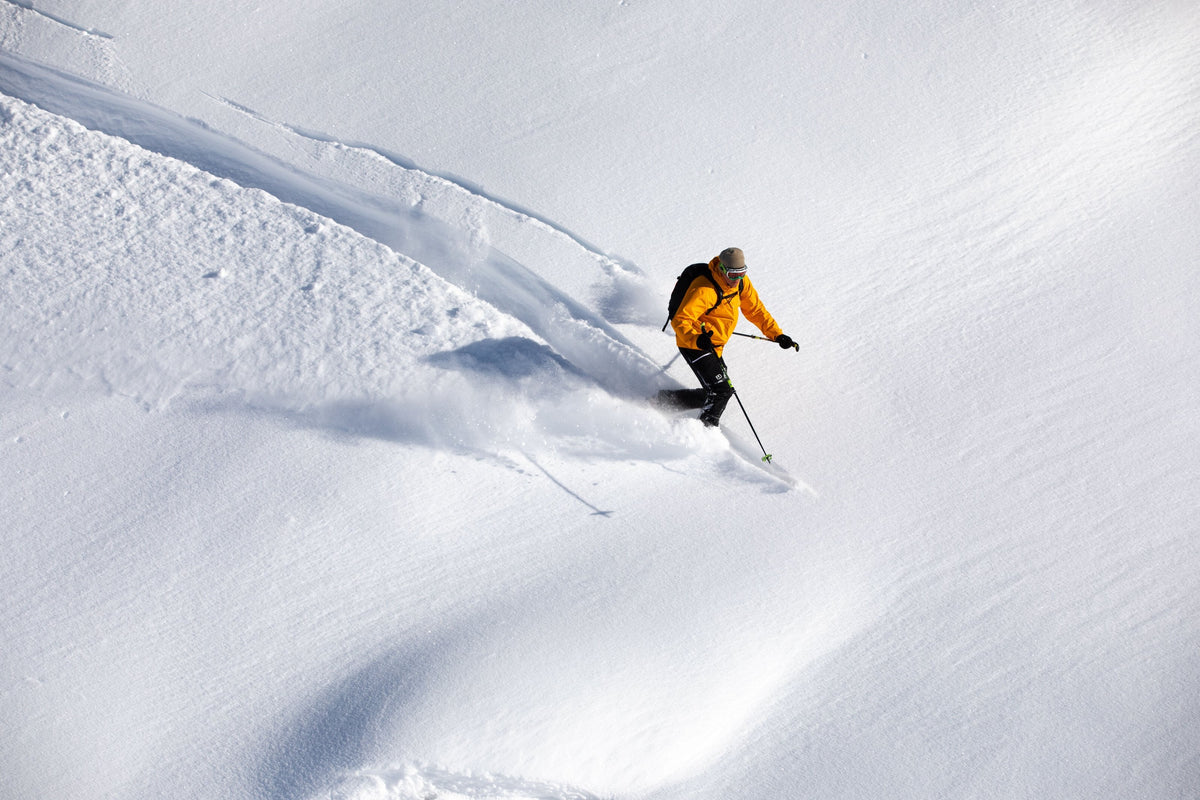 Skier in an orange jacket turning through deep powder
