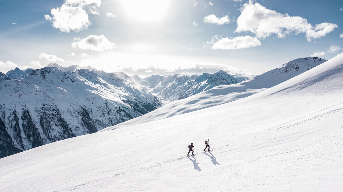 Two skiers on a sunlit snowy mountainside