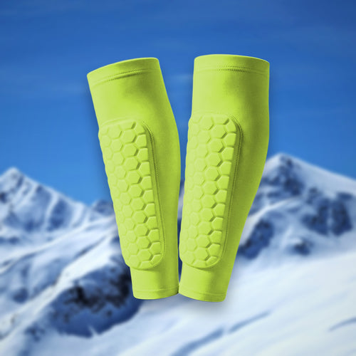 Pair of Shin Bang Pads in green with honeycomb shin padding, on a snowy mountain backdrop