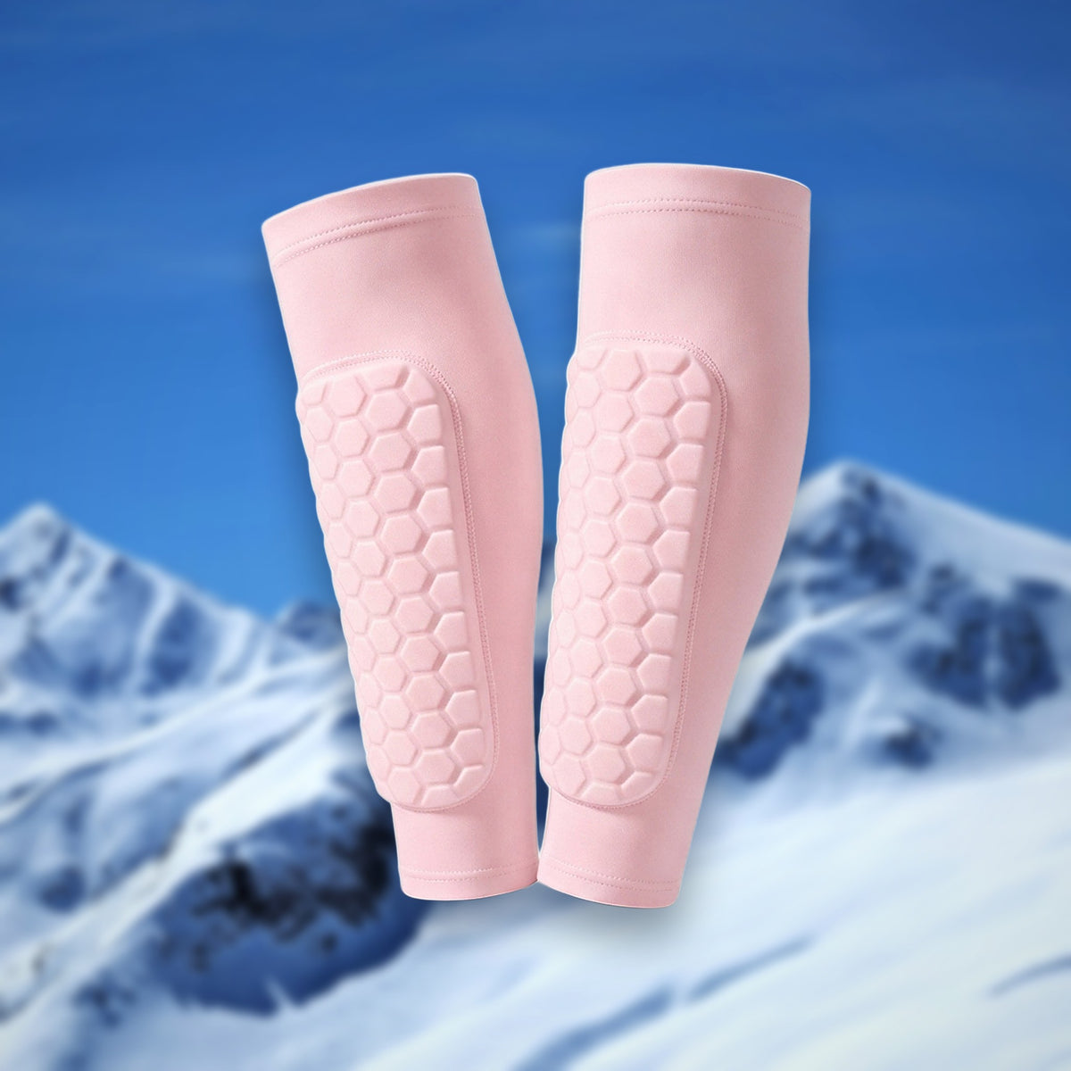 Pair of Shin Bang Pads in pink with honeycomb shin padding, on a snowy mountain backdrop