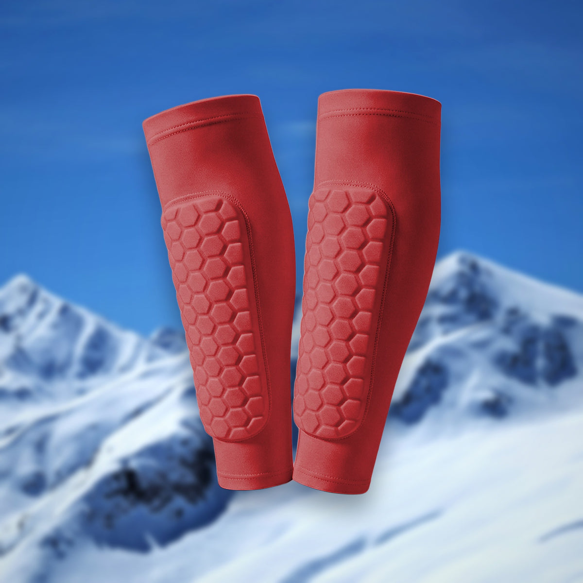 Pair of Shin Bang Pads in red with honeycomb shin padding, on a snowy mountain backdrop