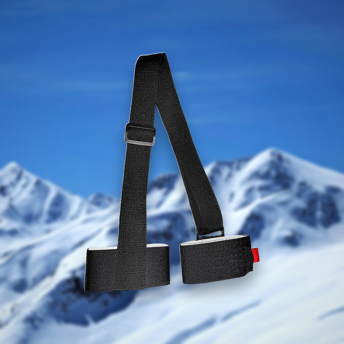 Alpine ski carry strap in black with two hook-and-loop ski loops, on a snowy mountain backdrop