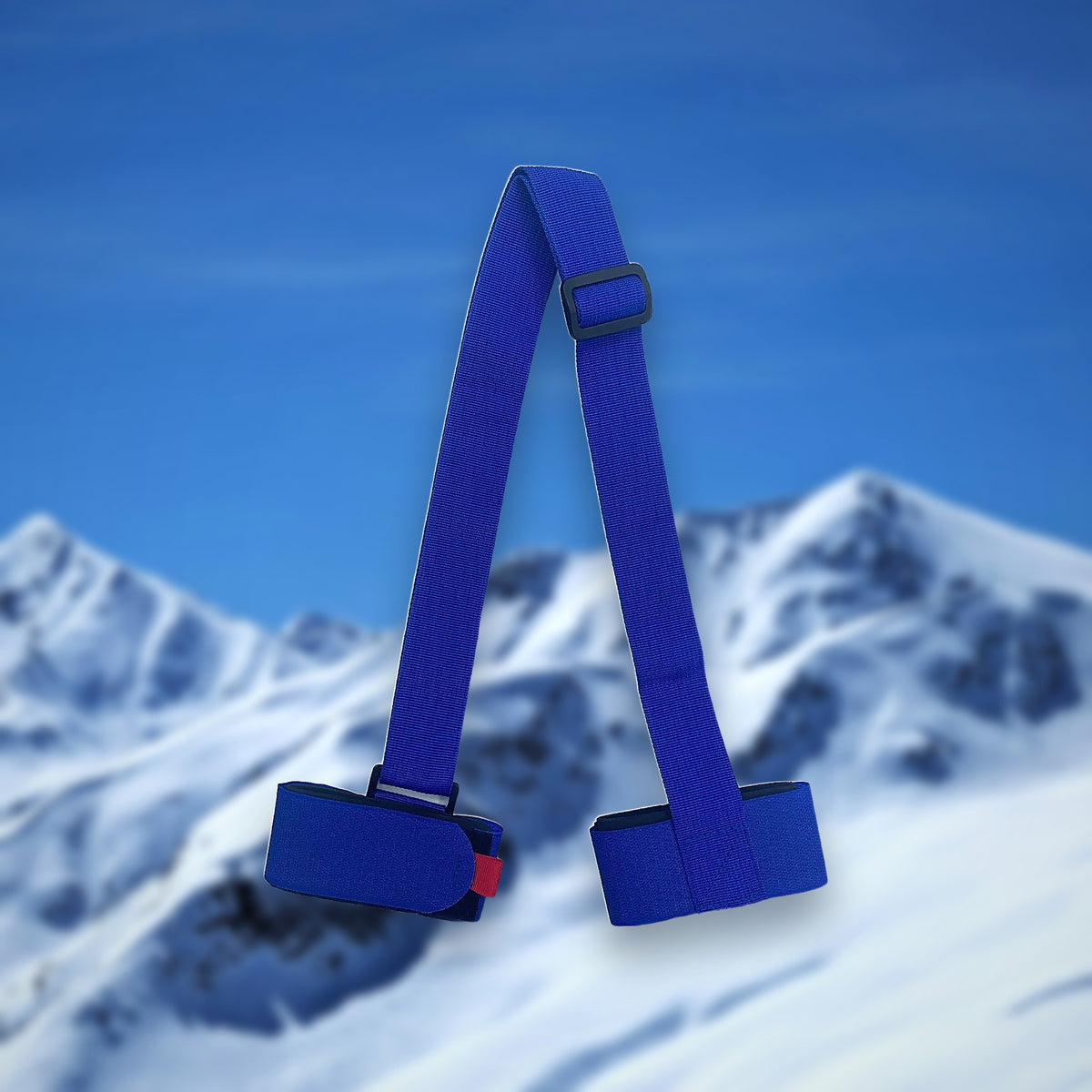 Alpine ski carry strap in blue with two hook-and-loop ski loops, on a snowy mountain backdrop