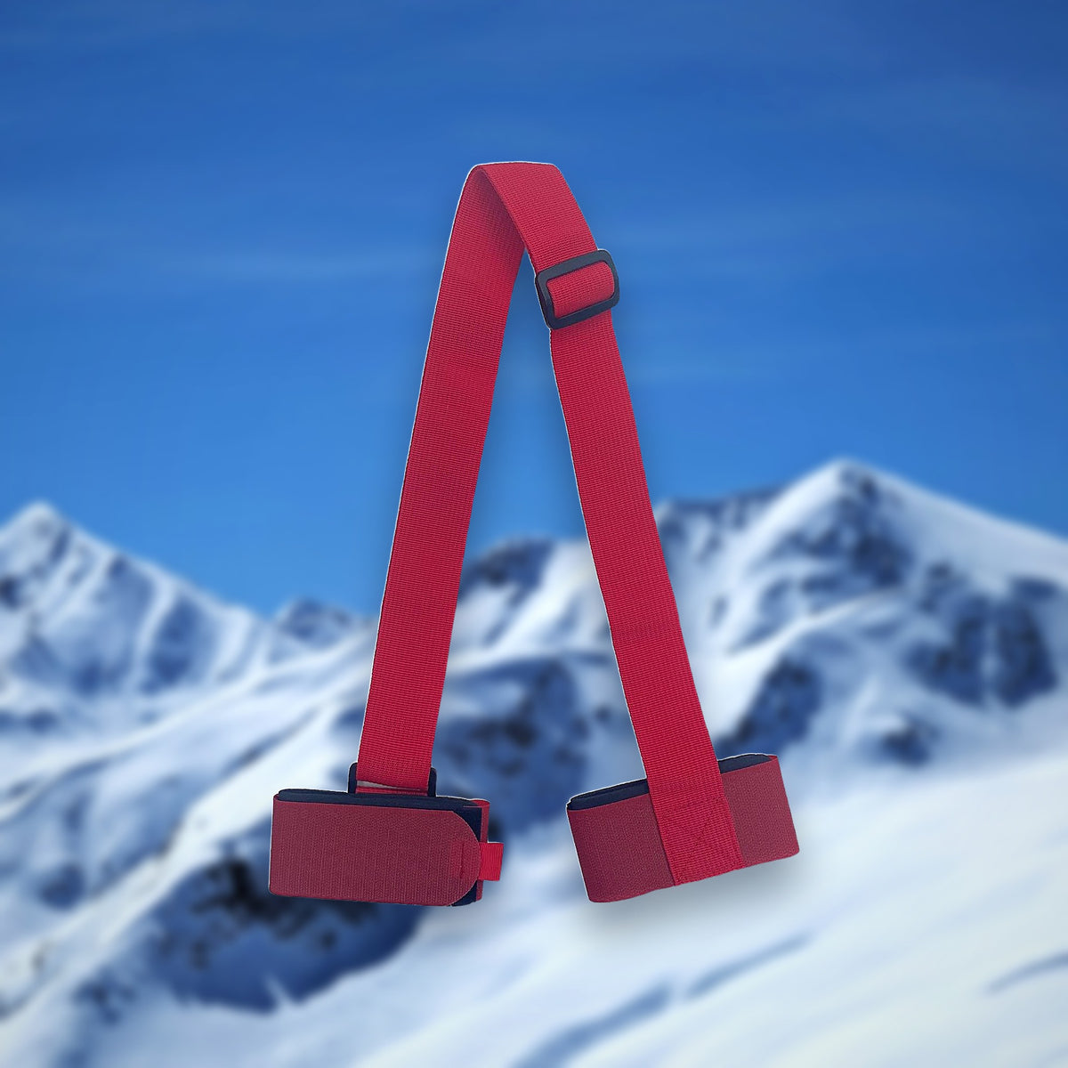 Alpine ski carry strap in red with two hook-and-loop ski loops, on a snowy mountain backdrop