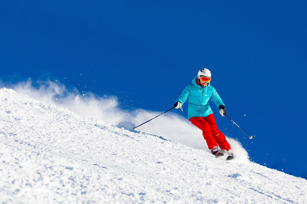 Skier carving through powder against a deep blue sky