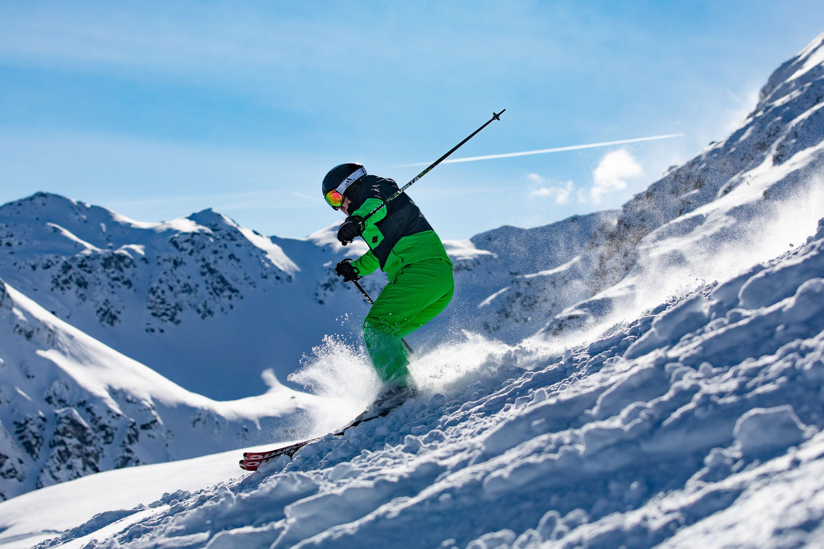 Skier turning through choppy powder below a mountain ridge