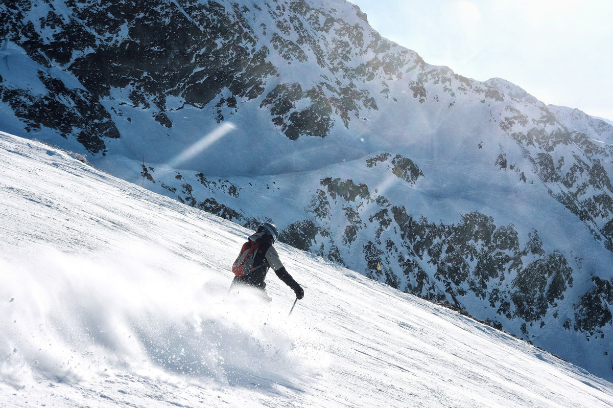 Skier kicking up snow on a steep alpine face